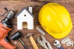 Wooden white house toy and construction tools on wooden background with copy space.Real estate concept, New house concept, Finance loan business concept, Repair maintenance concept